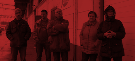 Fünf Dita Arbeiter_innen vor der Fabrik, die sie bewachen, damit die Maschinen nicht abtransportiert werden