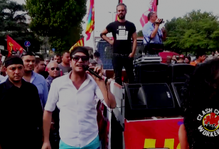 Demonstration, in der Menschenmenge ein Mann mit Mikrophon neben Lautsprecherwagen